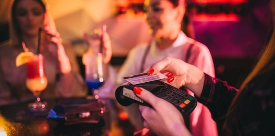 A person uses a POS system for credit card payment processing at a nightclub bar.