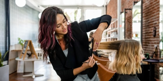 A stylist trims hair in a salon equipped with POS for smooth payment processing.