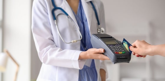 Doctor uses POS system for payment processing with card at payment terminal.