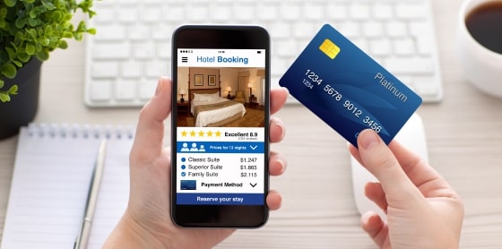 Person using smartphone with booking app and credit card next to POS essentials.