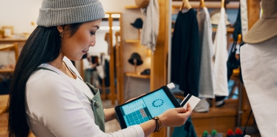 Retail worker uses POS system for credit card payment processing on a tablet.