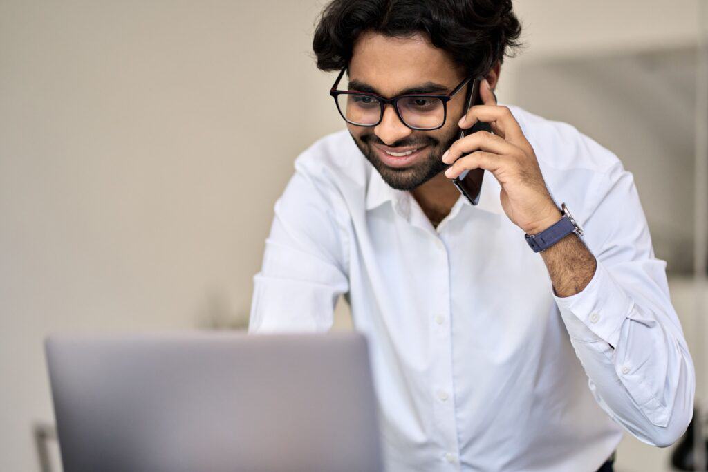 Man talks on the phone while looking at the computer - merchant account provider
