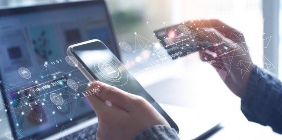 Person using smartphone and credit card near laptop for payment processing.