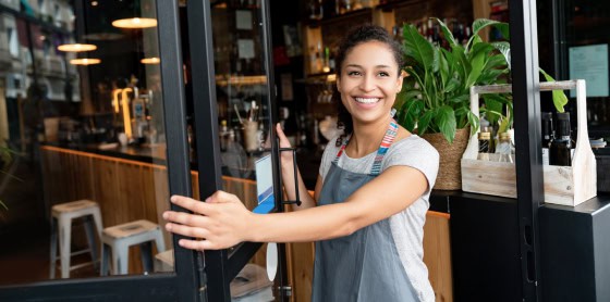 Person in apron enters café with POS system and credit card payment solutions.