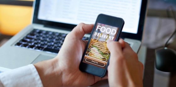 User ordering food on smartphone with POS system and payment gateway laptop.