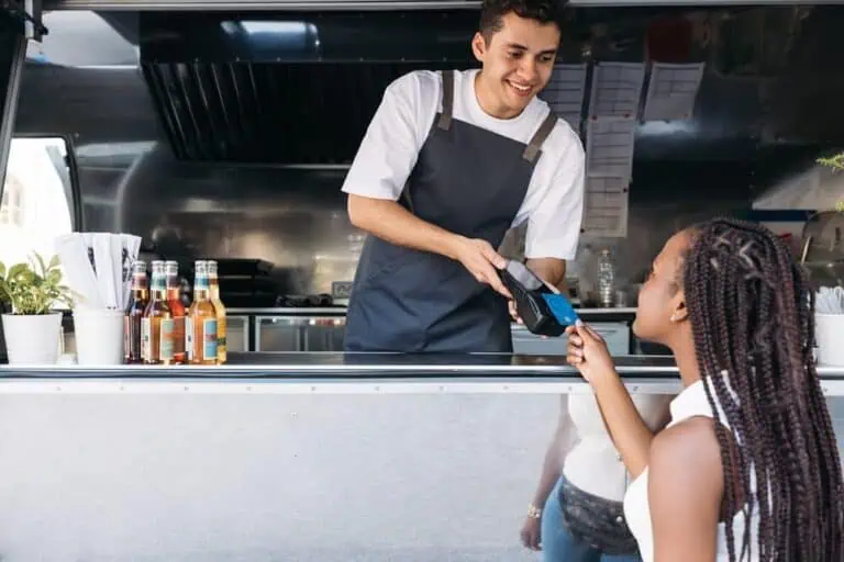 A merchant uses a POS system payment terminal for credit card processing at a food truck.