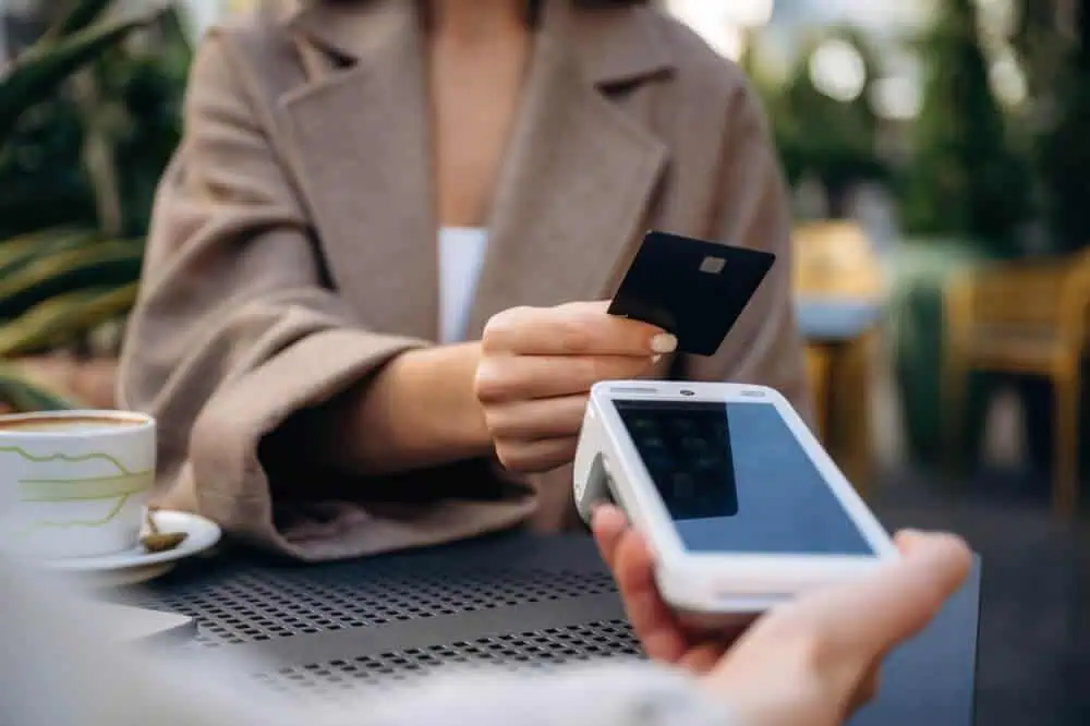 A customer uses a POS system for credit card payment processing at a café.